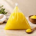 Desi ghee in a sealed pack with a bowl and wooden spoon of golden danedar ghee
