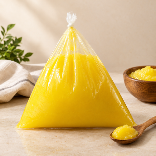 Desi ghee in a sealed pack with a bowl and wooden spoon of golden danedar ghee